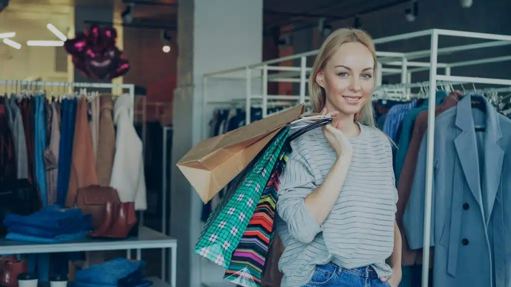 A woman holding many shopping paper bags in a boutique.