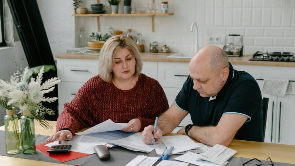 A man and a woman are budgeting at the kitchen table.