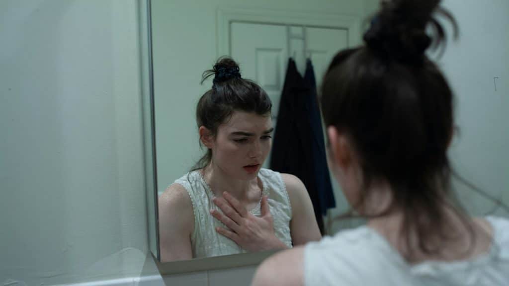 A woman looking at her face in the mirror.