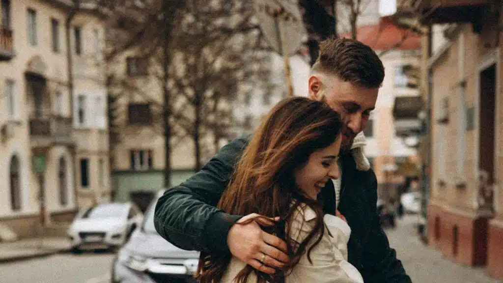A man holding a woman close as they walk on a street.