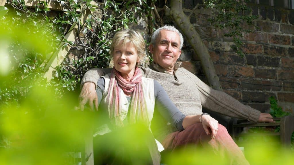 A man and a woman are sitting together on a bench.