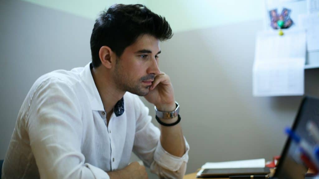 A young designer working on a laptop at his home office.