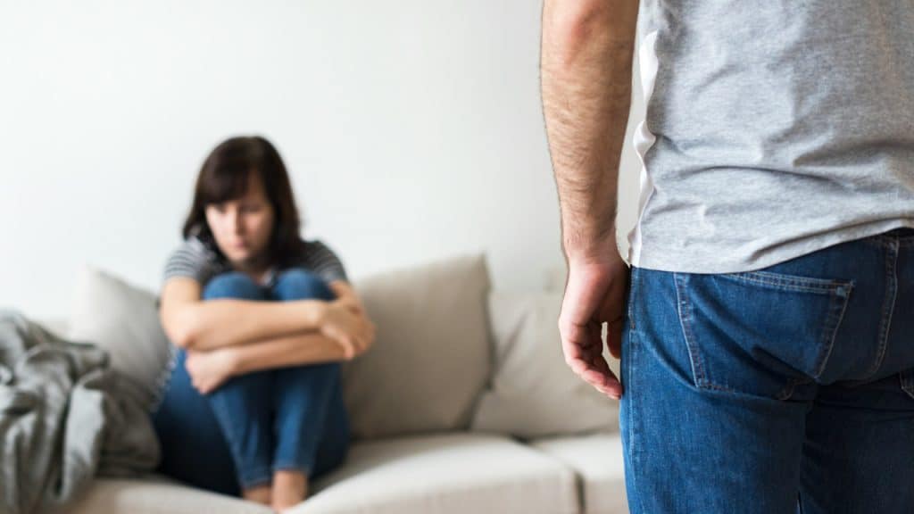 An unhappy argument is sitting on a sofa.