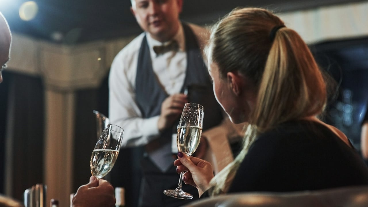 A man and a woman (drinking wine) making an order to waiter in a restaurant 