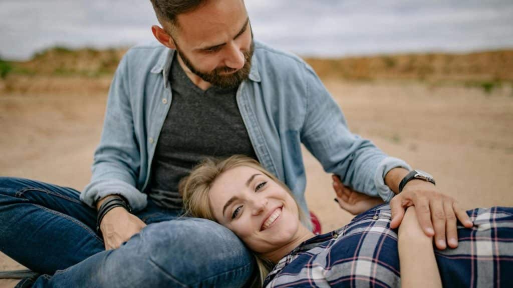 A couple relaxing together outdoors, with one resting their head on the other's lap.
