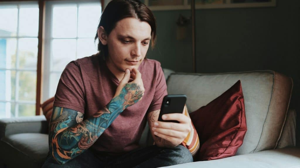 A man using an Android smartphone while sitting on a couch.