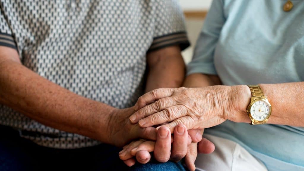 A close-up shot of an older couple's hands clasped together.