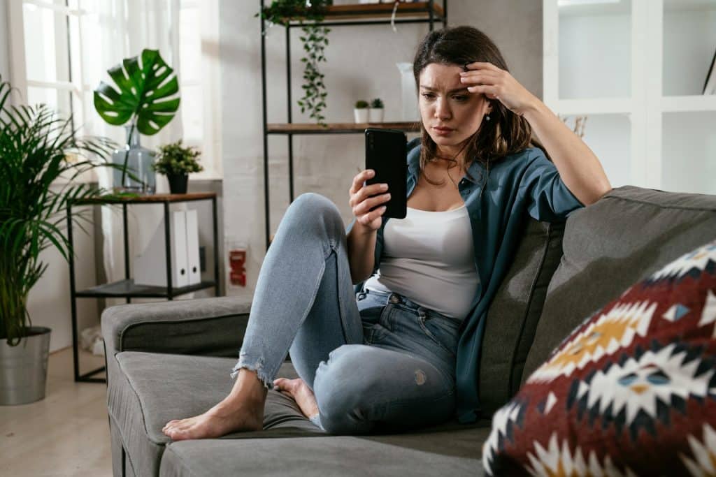 An upset woman looking at her phone.