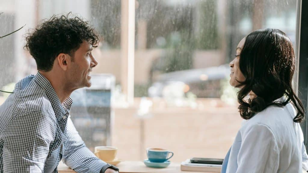 A man and woman talking and smiling at a café table.
