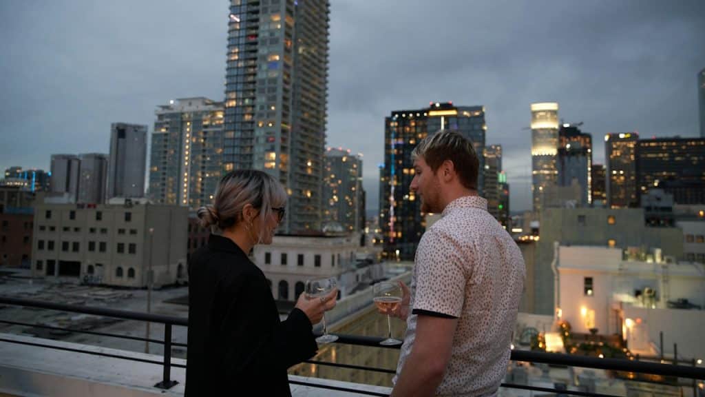 A man and a woman standing on a balcony overlooking a city.