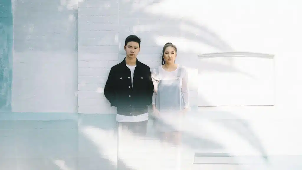 A man beside a woman while leaning against a wall.