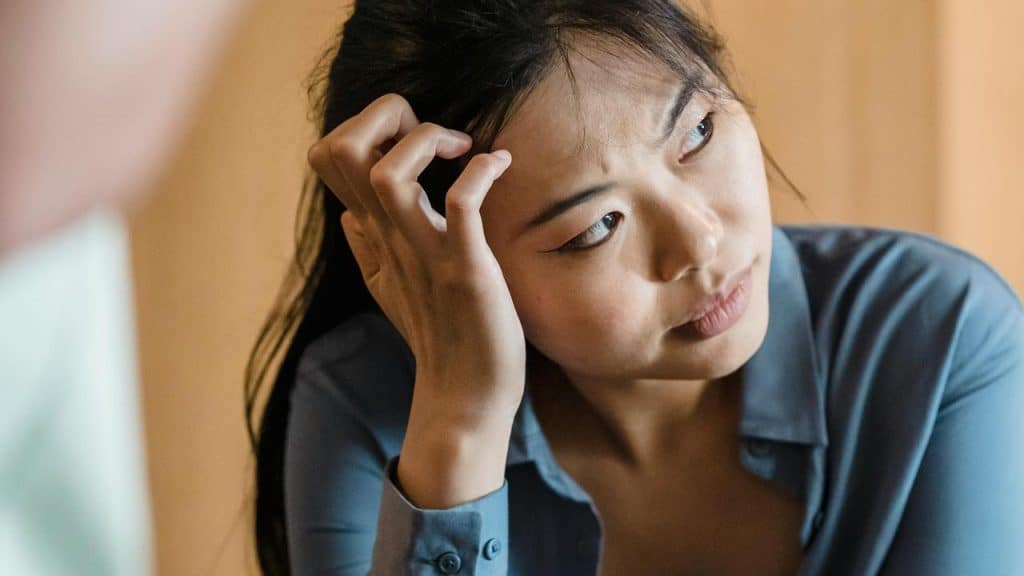 A woman resting her head on her hand with a thoughtful expression.