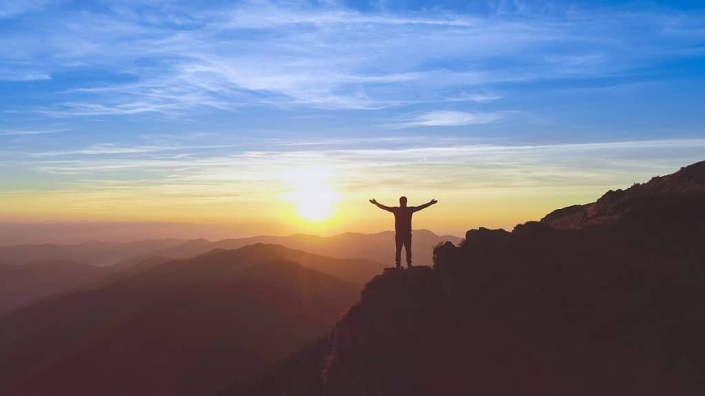 A man with his hands up on a mountain