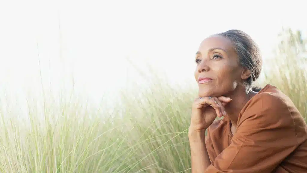 A woman sitting in a field of tall grass.