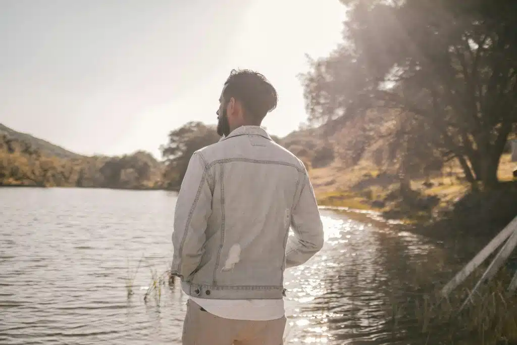 A man standing next to a lake.