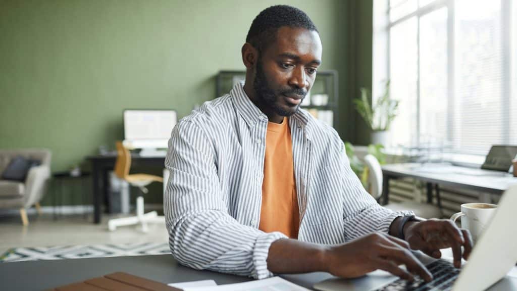 A man working on a laptop at a desk in an office.