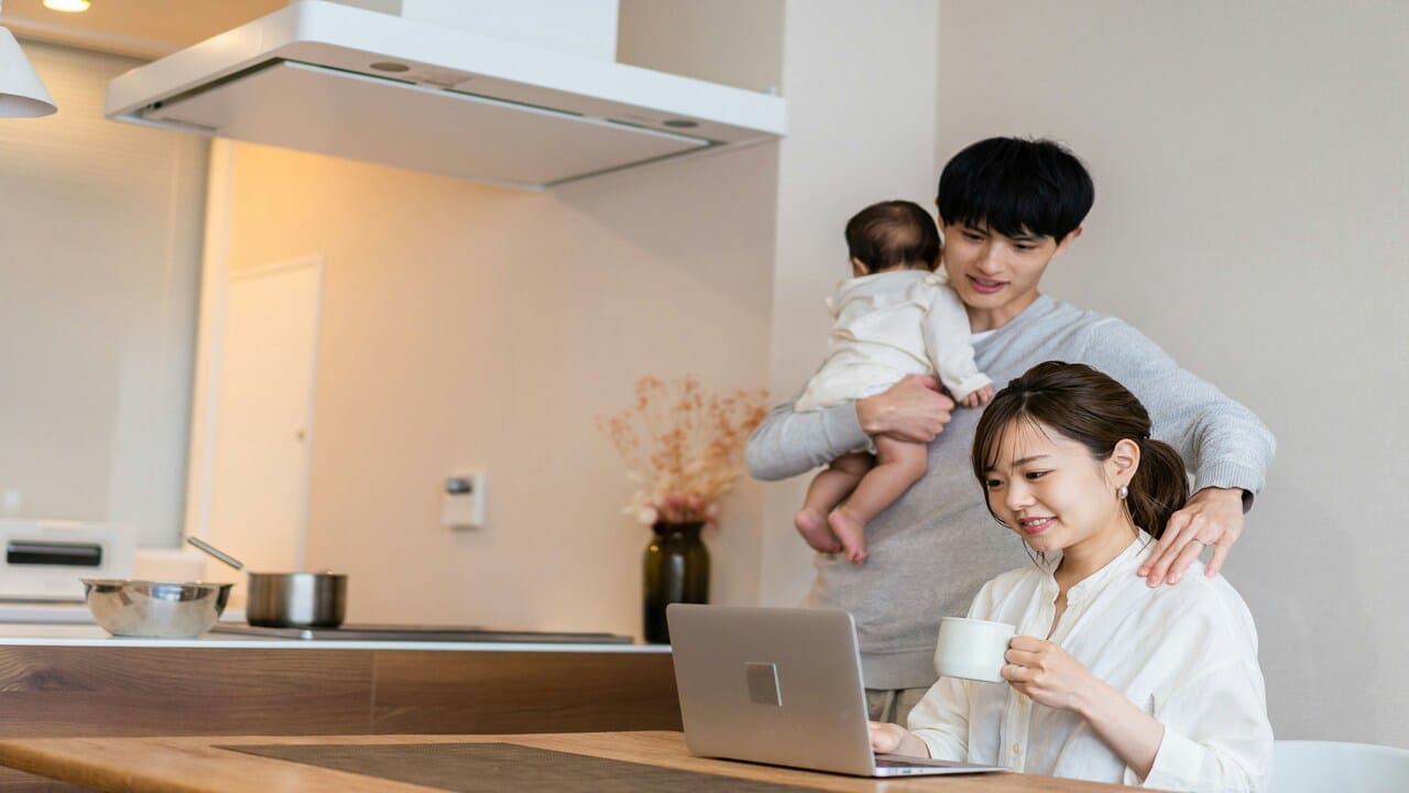A man carrying their baby while his wife works