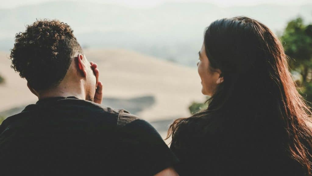 Man and woman with backs to the camera looking out over a blurred landscape.