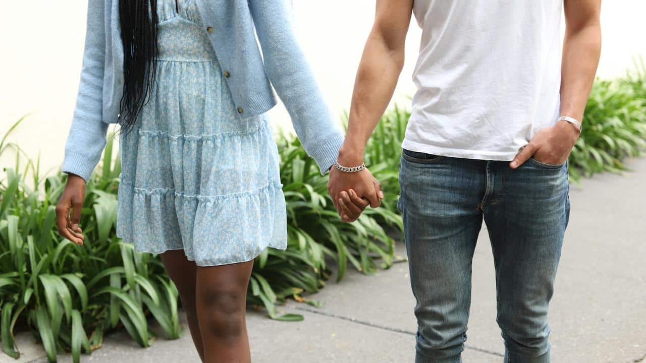 A couple walking hand in hand outdoors.