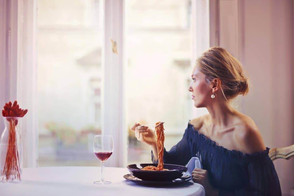 A woman eating pasta at a restaurant alone.