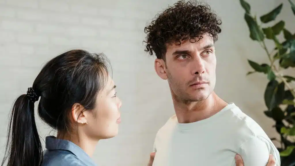A woman trying to talk to and hold a man who is turning away from her.