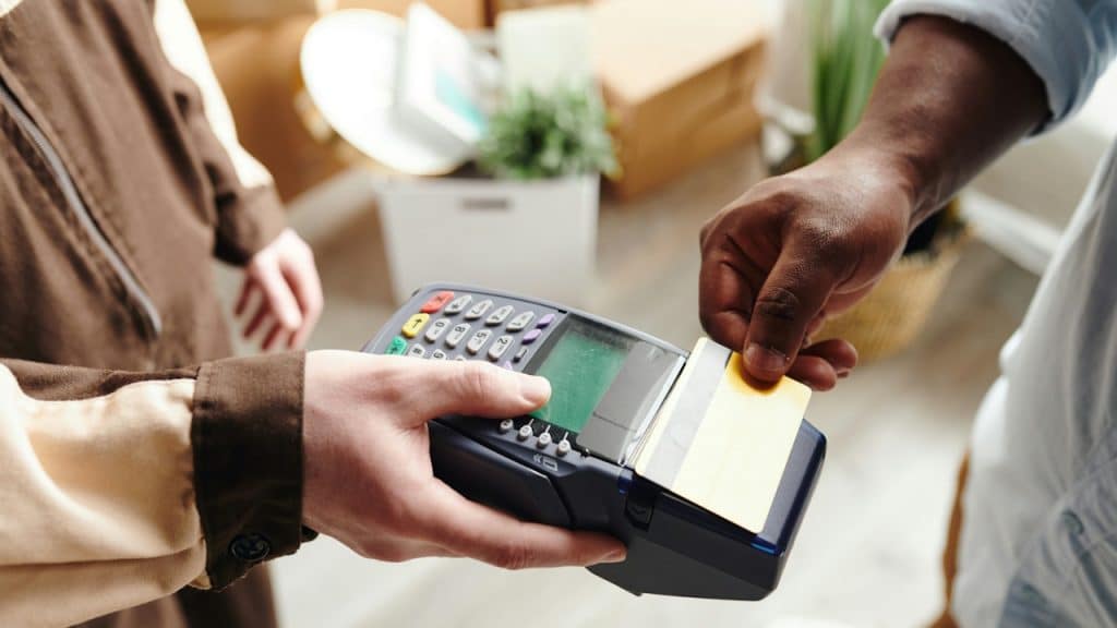 A person paying with a gold credit card using a handheld payment terminal.