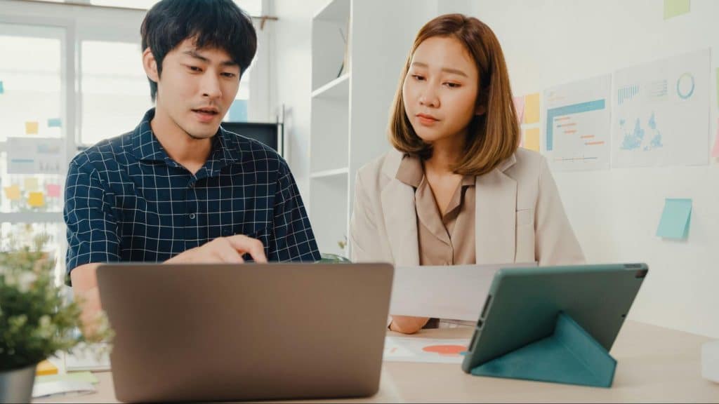 A man showing something to a woman from a laptop
