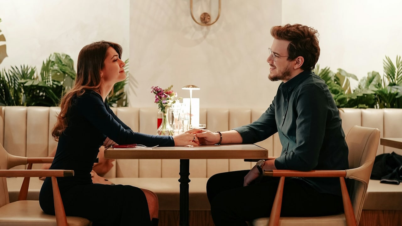 A couple on a date holding hands on a table.