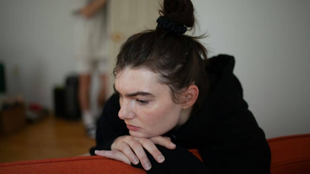 A woman sitting on a couch looking down.