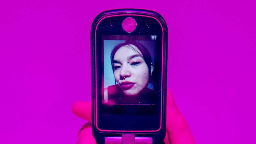 A person holding a cell phone with a woman’s picture on its screen.