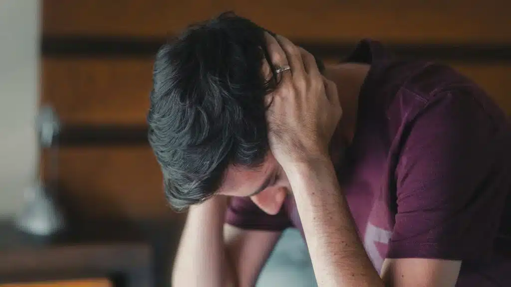 Close-up of a man from behind, hands clasped over his dark hair.