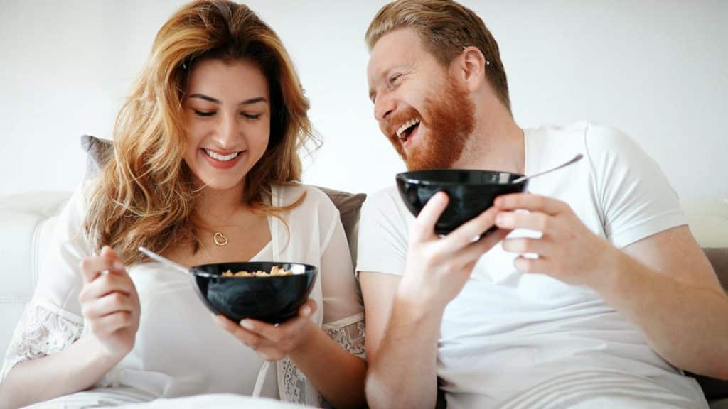 A man and woman laughing hard while having breakfast in the morning.