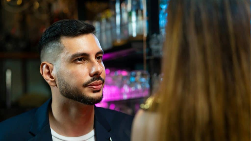 A handsome man looking at a woman in a bar.