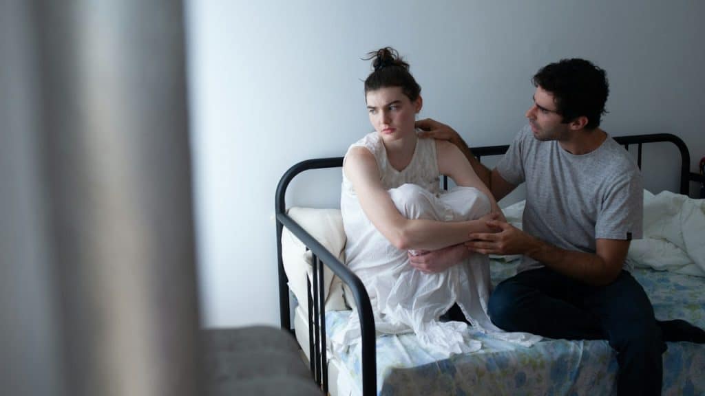 A man sitting next to a woman on a bed.