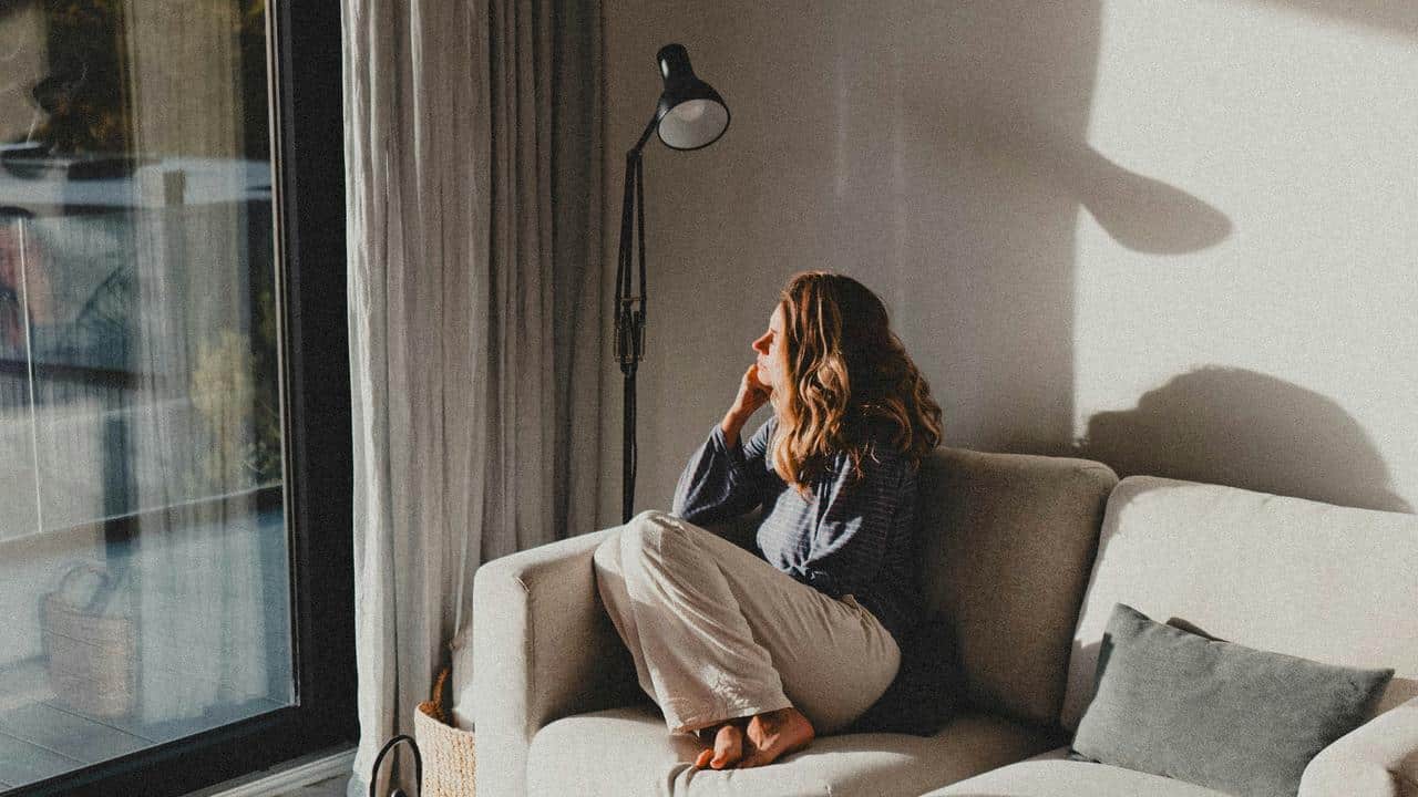 A woman sitting on a couch looking out the window.