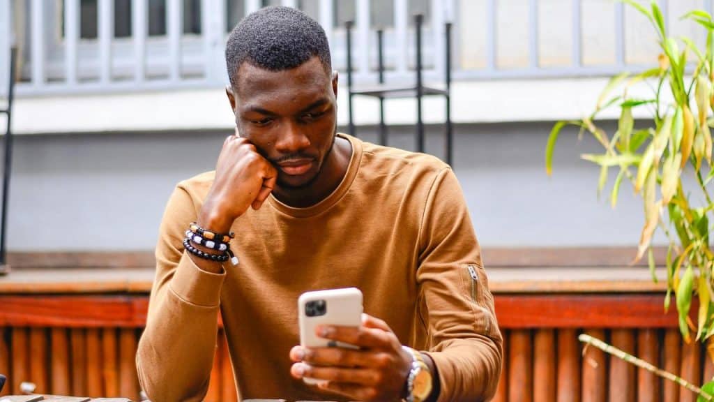 A man sitting outdoors looking at his phone.