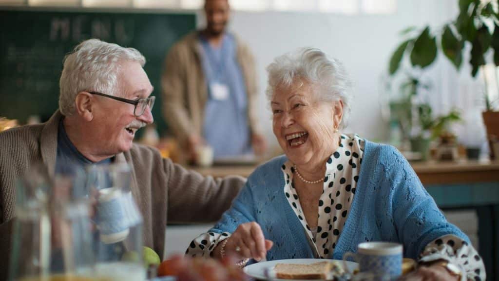 An older couple laughing together while enjoying a meal.