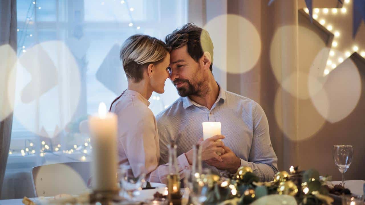 A couple sharing a romantic candlelit moment at dinner.