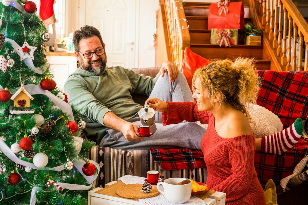 A couple having breakfast together in the living room near the Christmas tree.