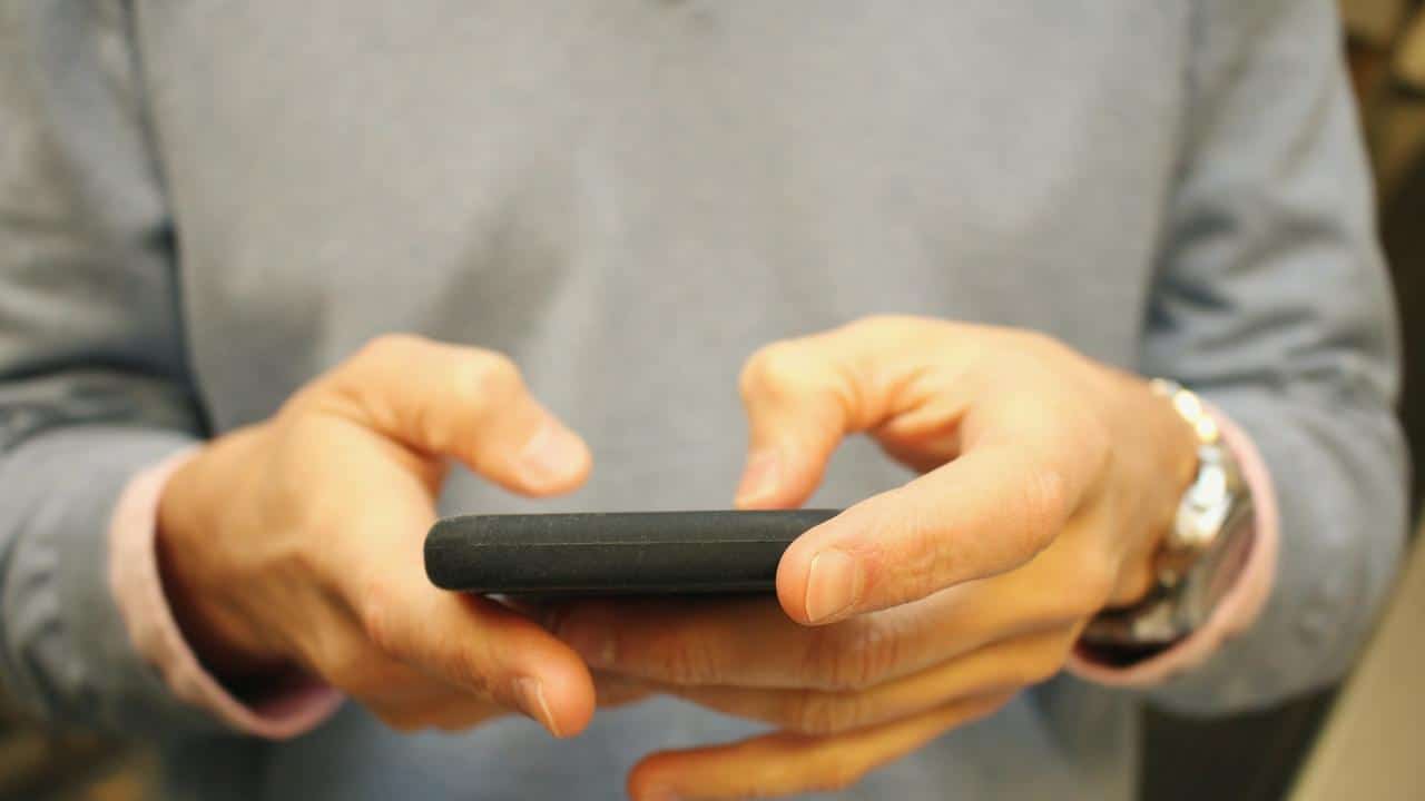 A person wearing a gray sweatshirt using a smartphone.