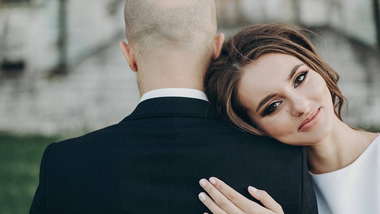 A woman resting her head on a man’s shoulder who has his back to the camera.