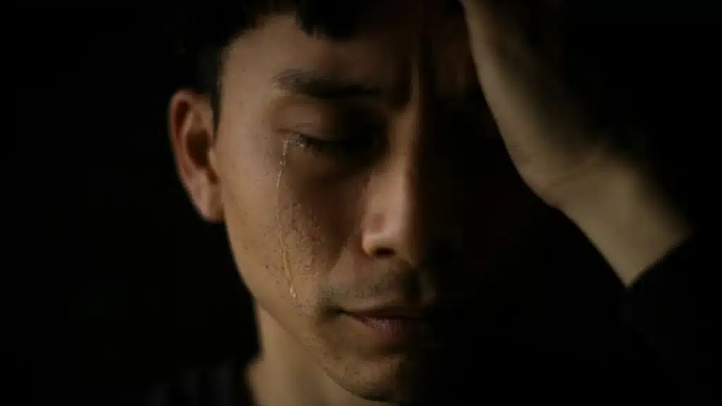 A close-up of a man crying with tears.