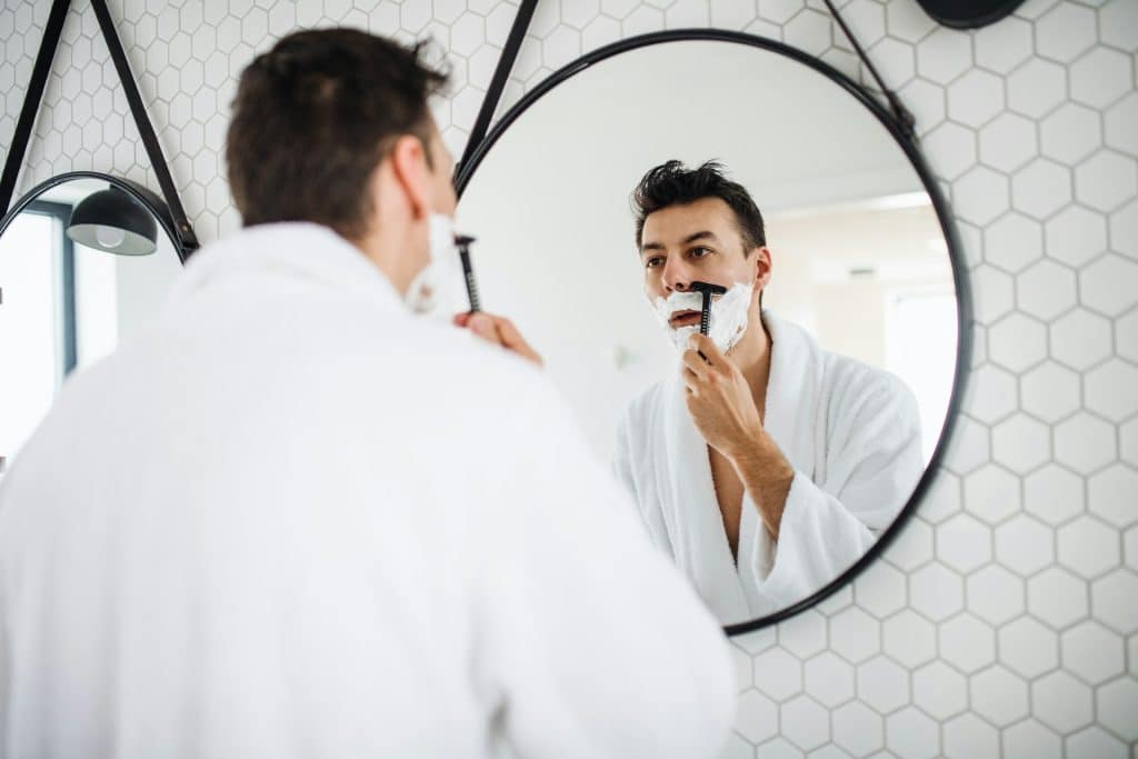 A man shaving in the bathroom.