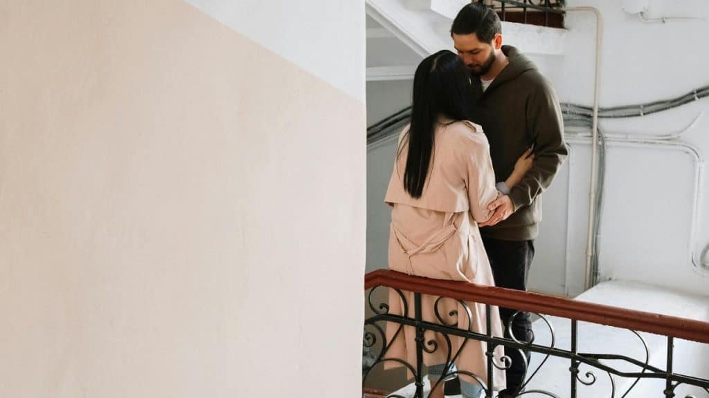 A couple standing close together on a stair landing.
