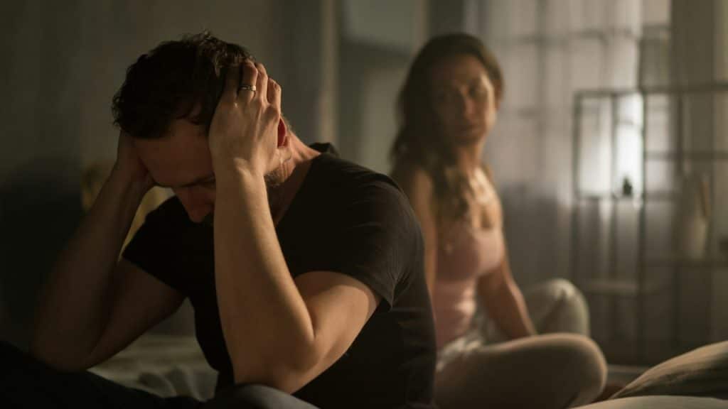 A husband and wife arguing in bed about relationship problems.