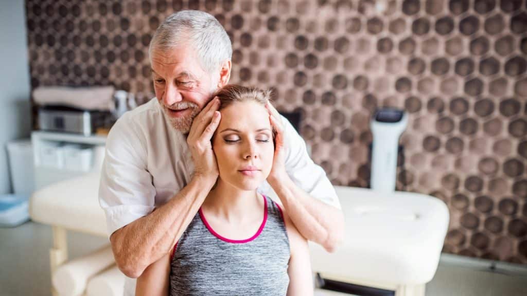 A senior male physiotherapist working with a young female patient.