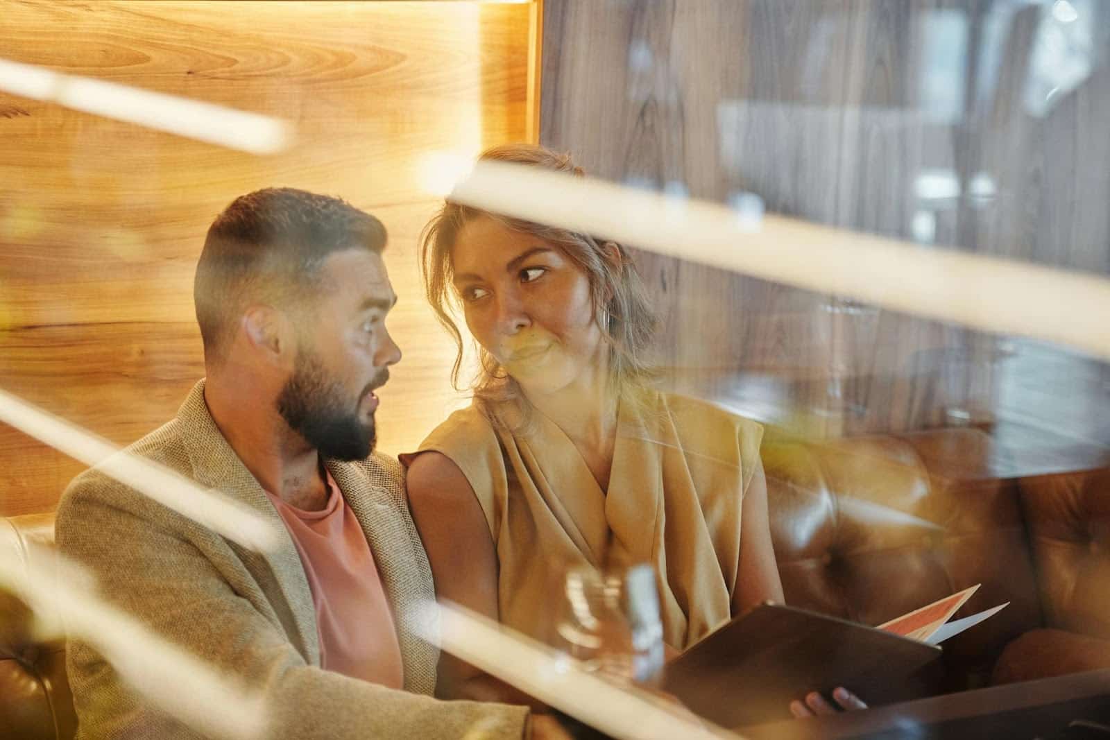 The woman holding the menu is looking at the man.