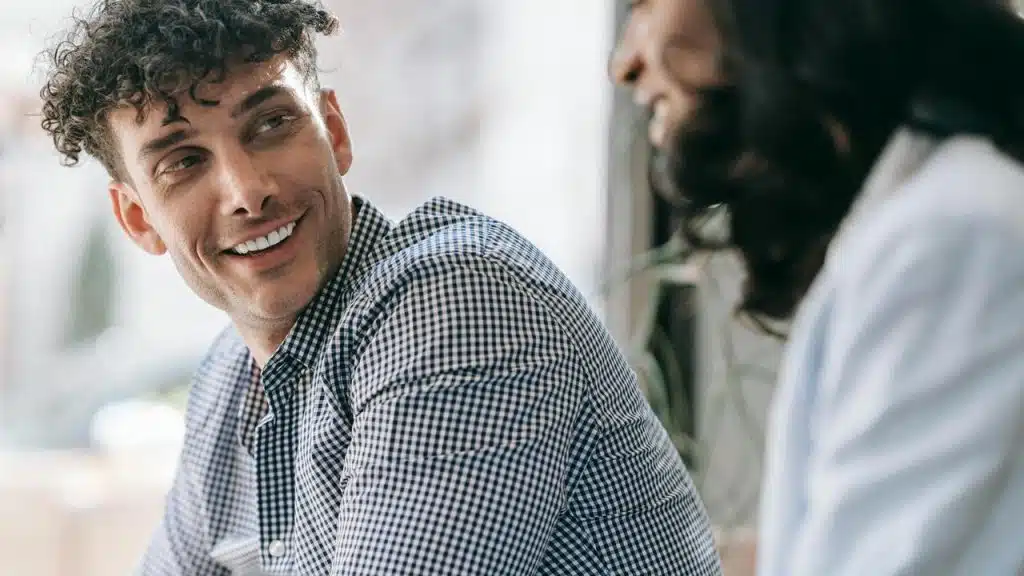 A man smiling while talking to a woman.