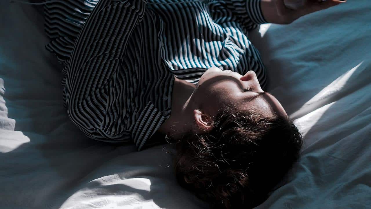 A woman lying on a bed in sunlight.