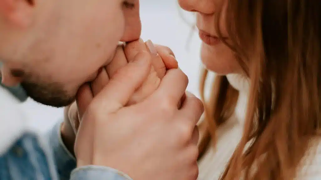 A man gently kissing a woman’s hand in a close-up moment.